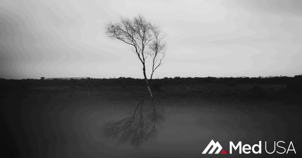 black and white image of a tree in the desert with white and red med usa logo