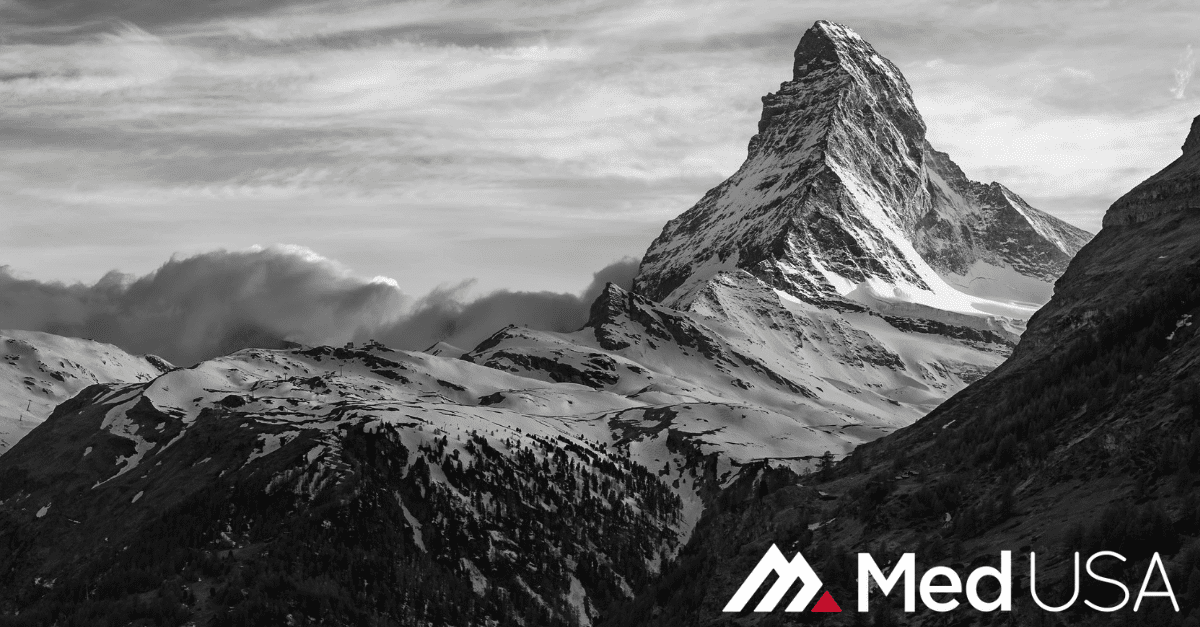 black and white photo of a mountain top and clouds with white and red Med USA logo
