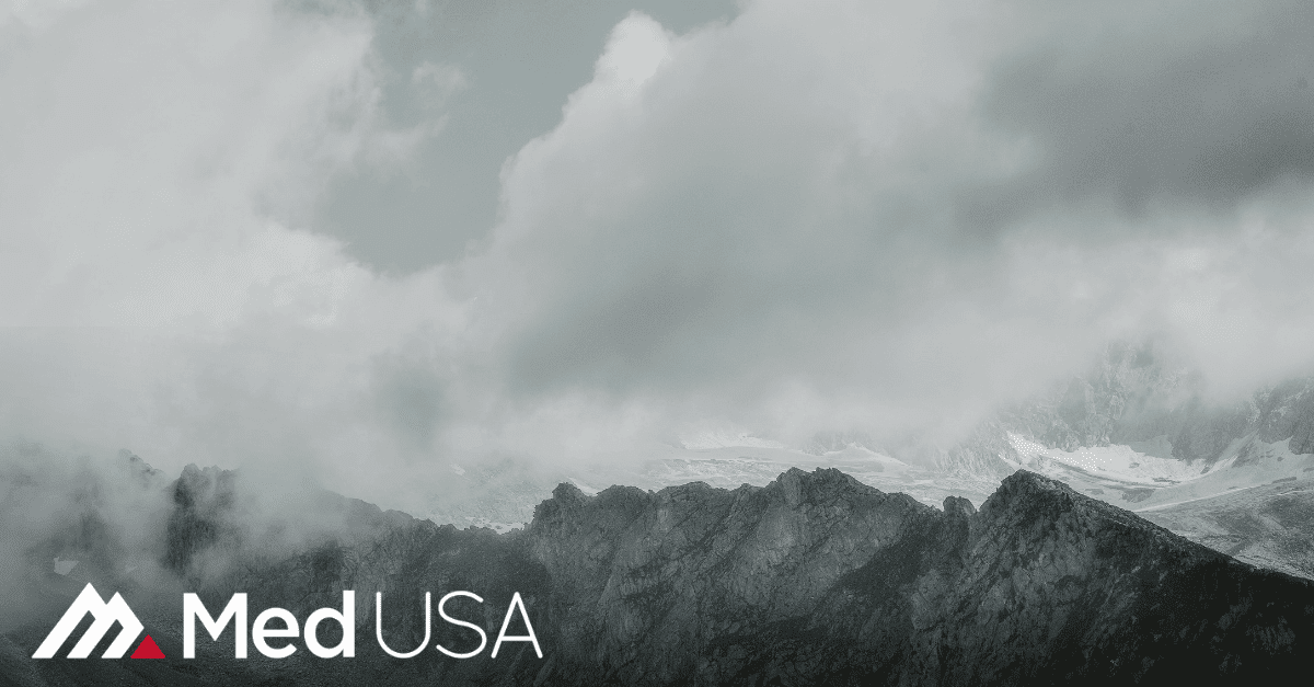 black and white image of clouds and mountain top with white and red med usa logo
