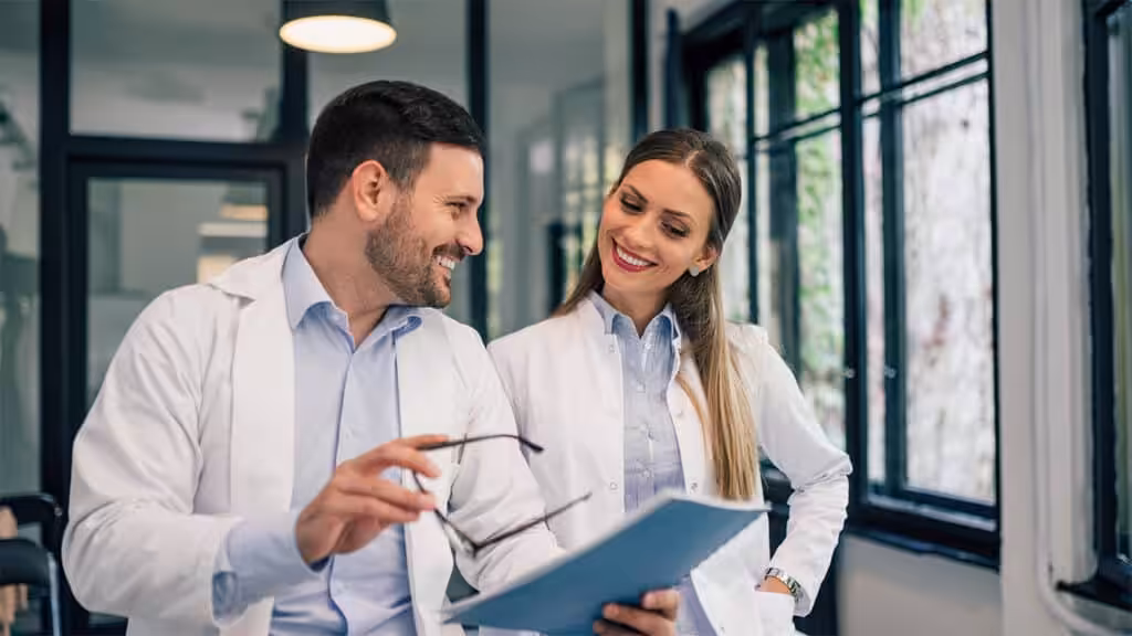 Two healthcare professionals having a discussion while looking at a clipboard