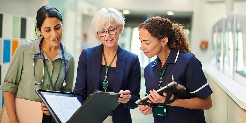 Healthcare administrators discussing data on a clipboard