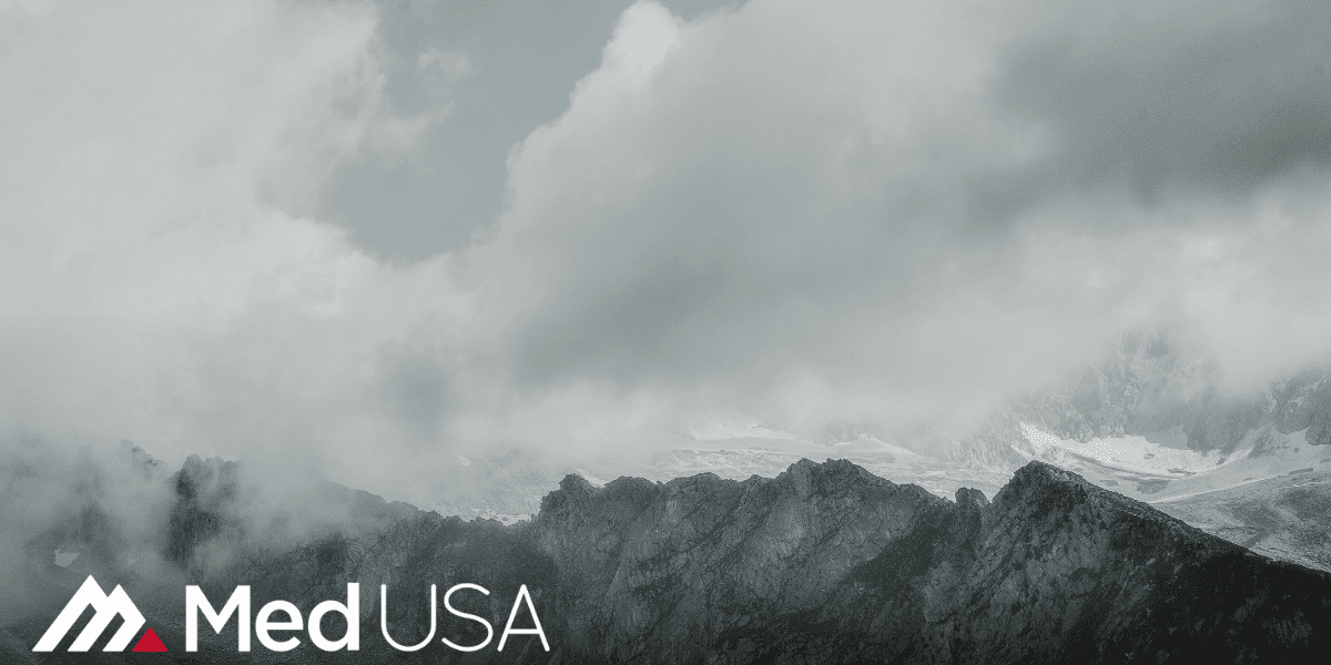 black and white image of clouds and mountain top with white and red med usa logo