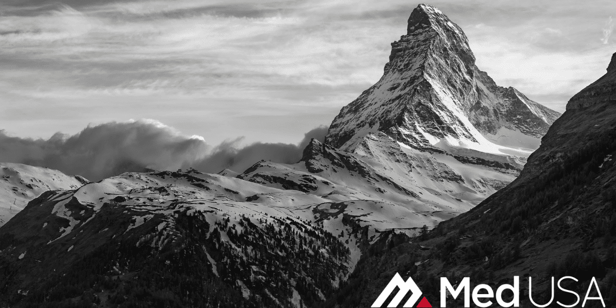 black and white photo of a mountain top and clouds with white and red Med USA logo